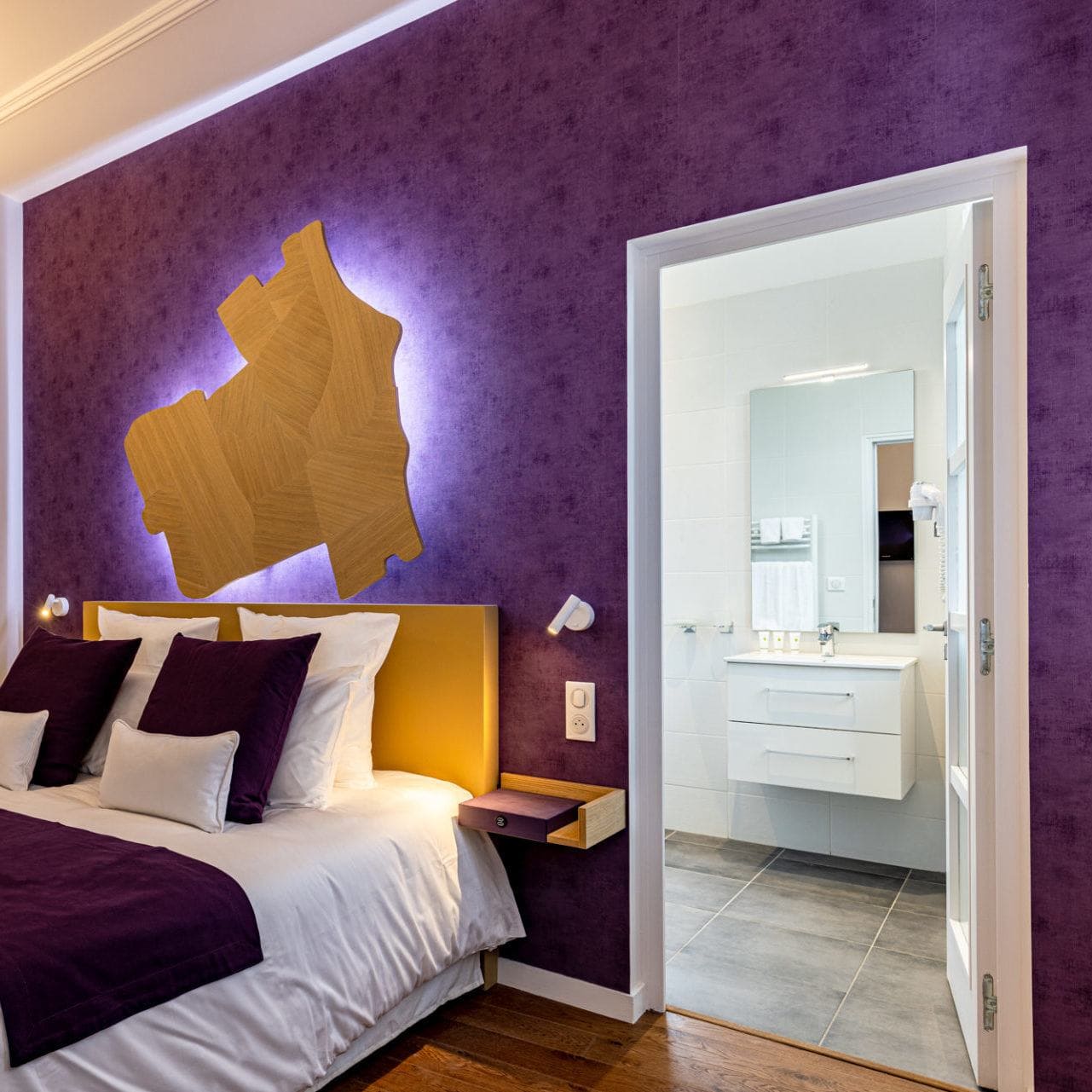Charmante chambre avec lit deux places avec télévision et fauteuil, tons violets