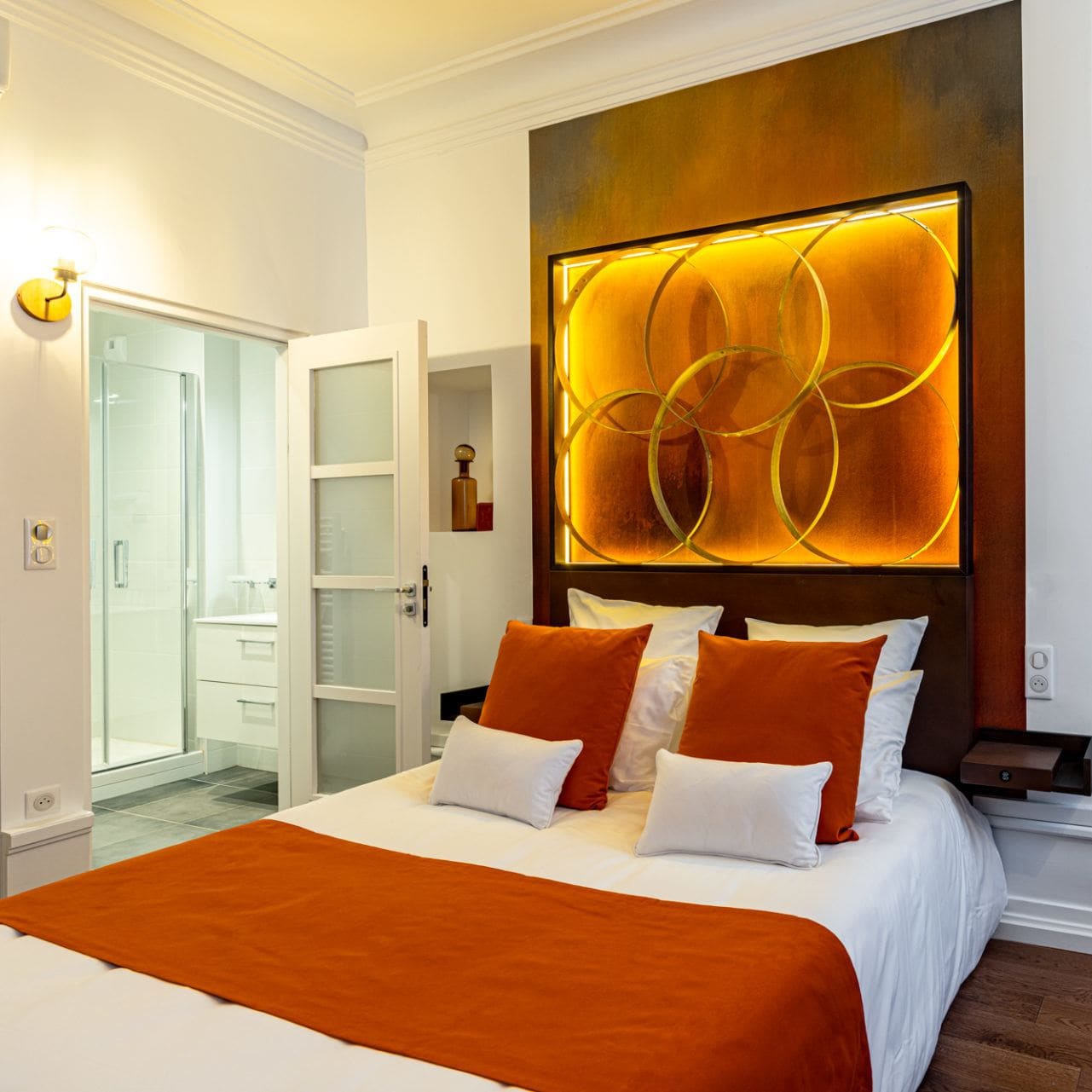 Charmante chambre avec lit deux places avec télévision et fauteuil, tons oranges