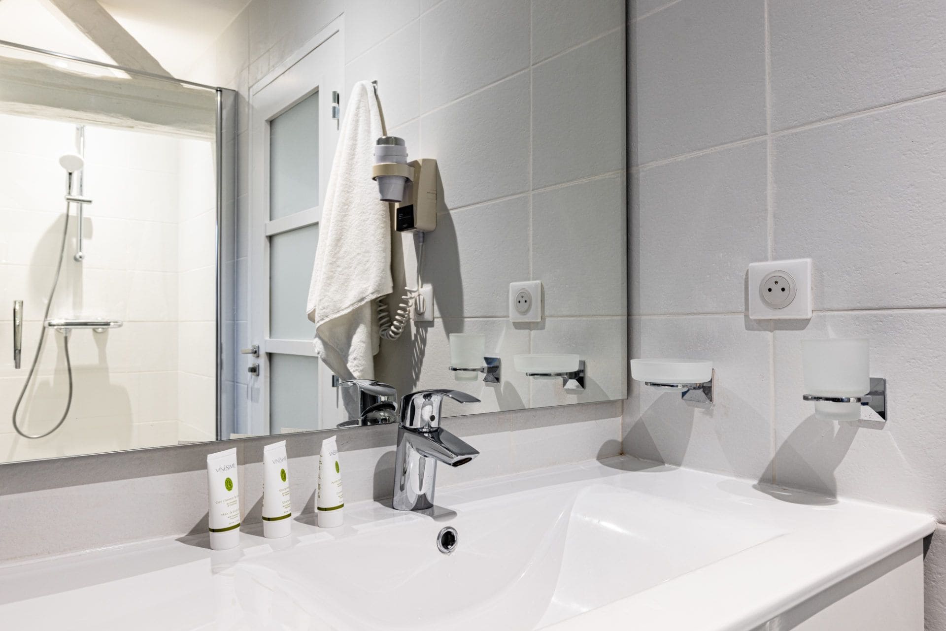 Salle de bain équipée d'un sèche cheveux. Douche